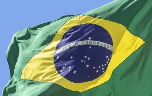 detail of Brazil flag fluttering in the blue sky. Translation: order and progress.