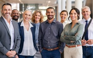 Portrait of successful group of business people at modern office looking at camera. Portrait of happy businessmen and satisfied businesswomen standing as a team. Multiethnic group of people smiling and looking at camera.