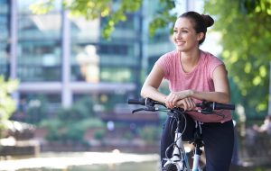 Young Woman Cycling Next To River In Urban Setting