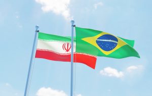 Brazil and Iran, two flags waving against blue sky. 3d image