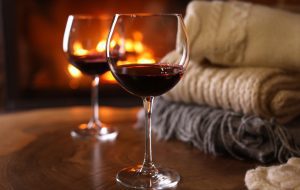 Glasses of wine, knitwear and blurred fireplace on background