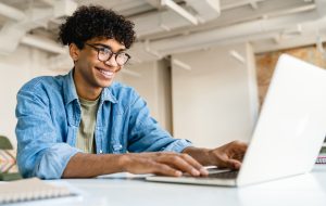 Happy smiling afro businessman using laptop at the desk in office