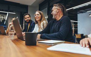 Successful group of businesspeople having a briefing in a boardroom. Happy businesspeople smiling while working together in a modern workplace. Diverse business colleagues collaborating on a project.