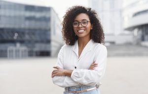 Smiling african-american student girl in a city. Woman looking at camera. People, city life, student lifestyle concept