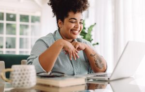 Positive woman video calling using laptop. Businesswoman teleconferencing on laptop while working from home.