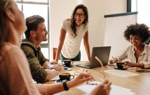 Group of multi ethnic executives discussing during a meeting. Business man and woman sitting around table at office and smiling.