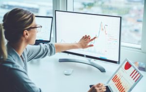 Business woman study financial market to calculate possible risks and profits.Female economist accounting money with statistics graphs pointing on screen of computer at desktop. Quotations on exchange