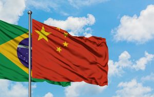 Brazil and China flag waving in the wind against white cloudy blue sky together. Diplomacy concept, international relations.