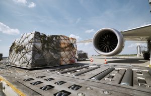 Preparation fright airplane before flight. Loading of cargo containers against jet engine of plane.
